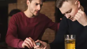 A sober friend taking away his drunk friend's car keys,