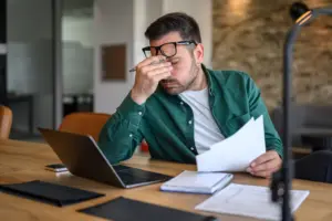 A man looking stressed while looking at paperwork.