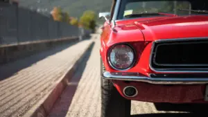 A front shot of a red classic car on the road.