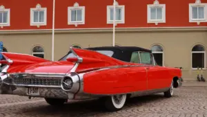 A red classic car parked in front of a building.