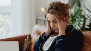 A blond woman looking stressed at her computer. 