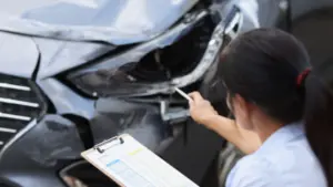 An inspector assessing the damage of a broken headlight.