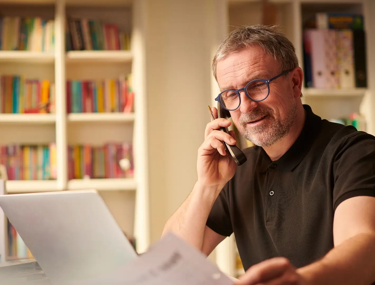 An old man calling his lawyer while looking at paperwork.