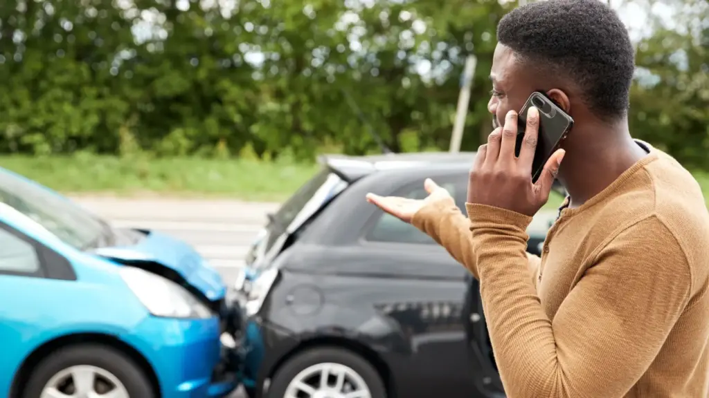 A man on the phone after getting involved in a car accident.