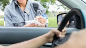 An officer writing a ticket to a driver.