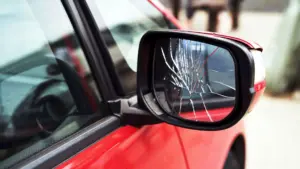 A red car with a cracked side mirror.