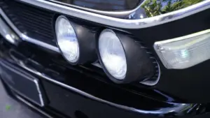 A close-up of a black car with no front license plate.