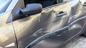 A car's drivers side door with a huge dent.