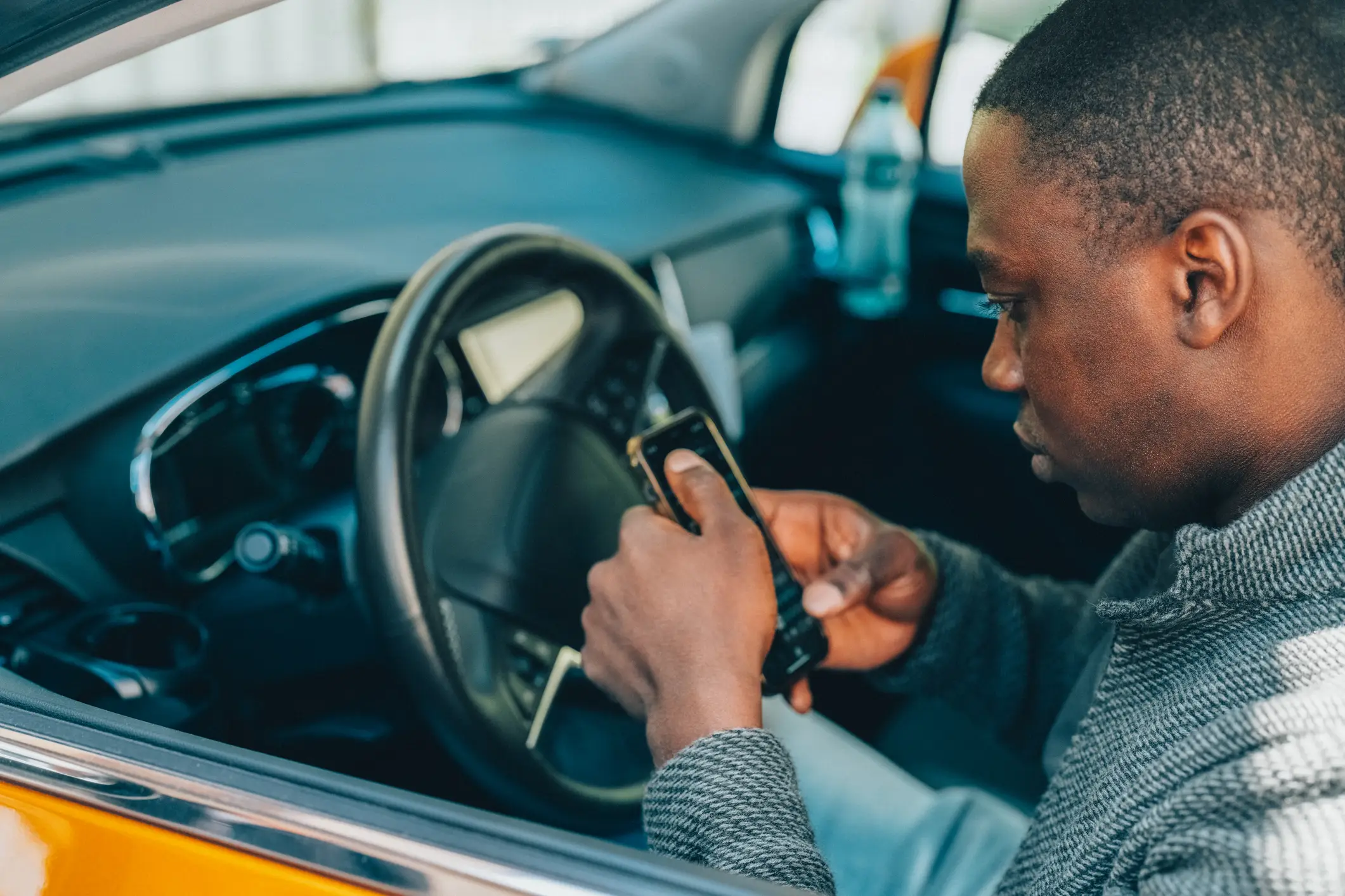 A rideshare driver looking on his phone, trying to figure our Uber and Lyft's insurance policy.