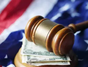 A gavel with money and an American flag underneath.