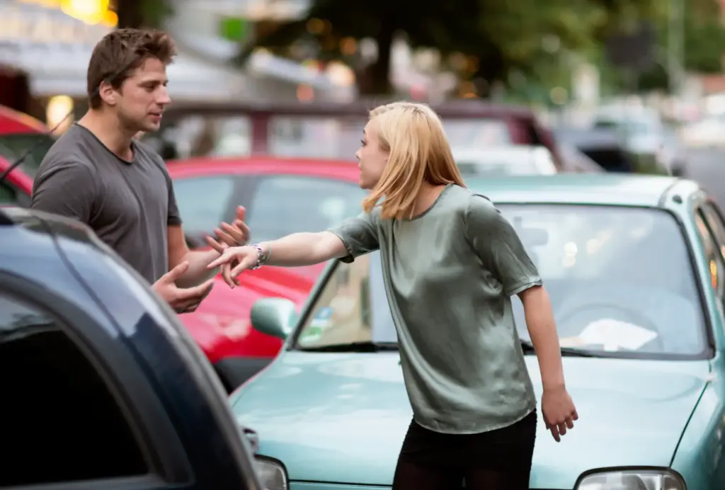 A blond woman arguing with a man after a car accident.