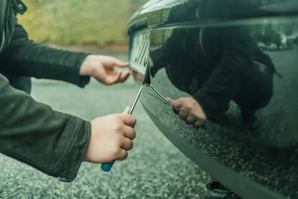 A man installing a license plate bracket on a car.