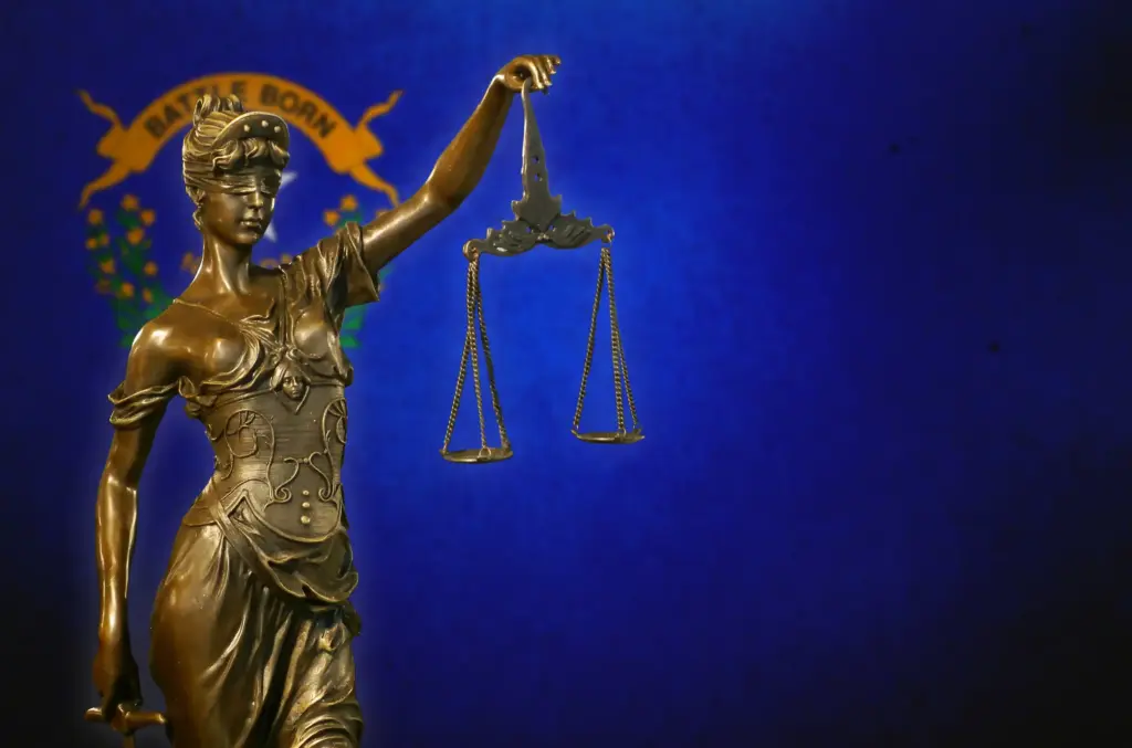 The Nevada state flag with a statue of lady justice in front.