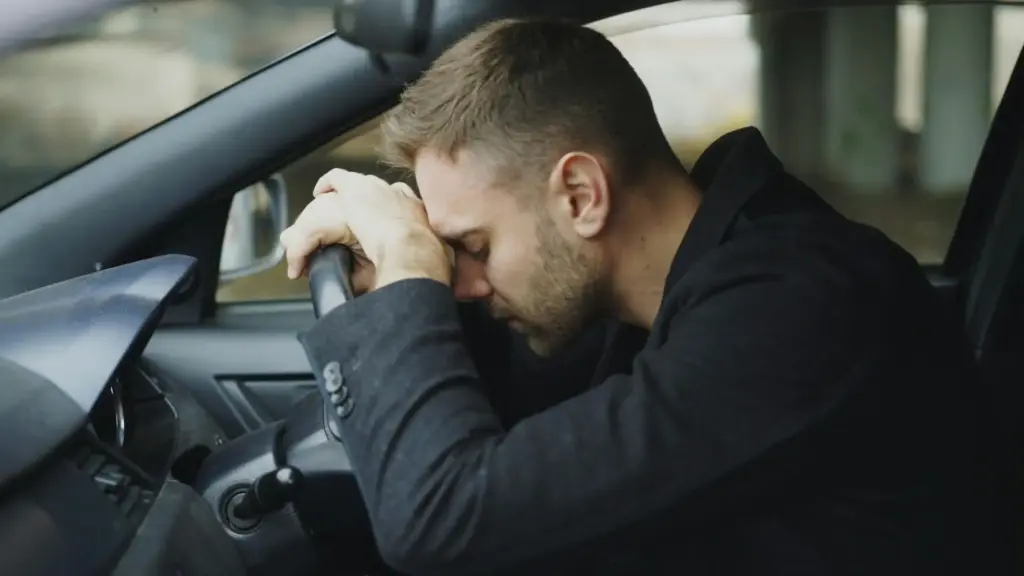 A driver putting his head on the steering wheel after causing a car accident.