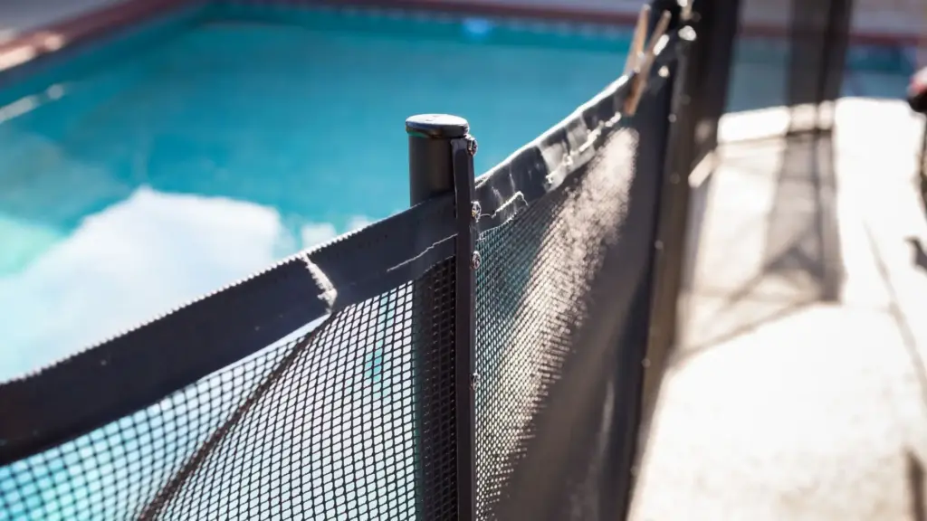 A thin black pool fence to prevent child drowning.