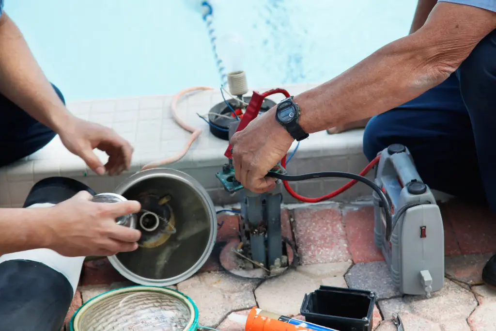 Two pool working on a pool's electric system.