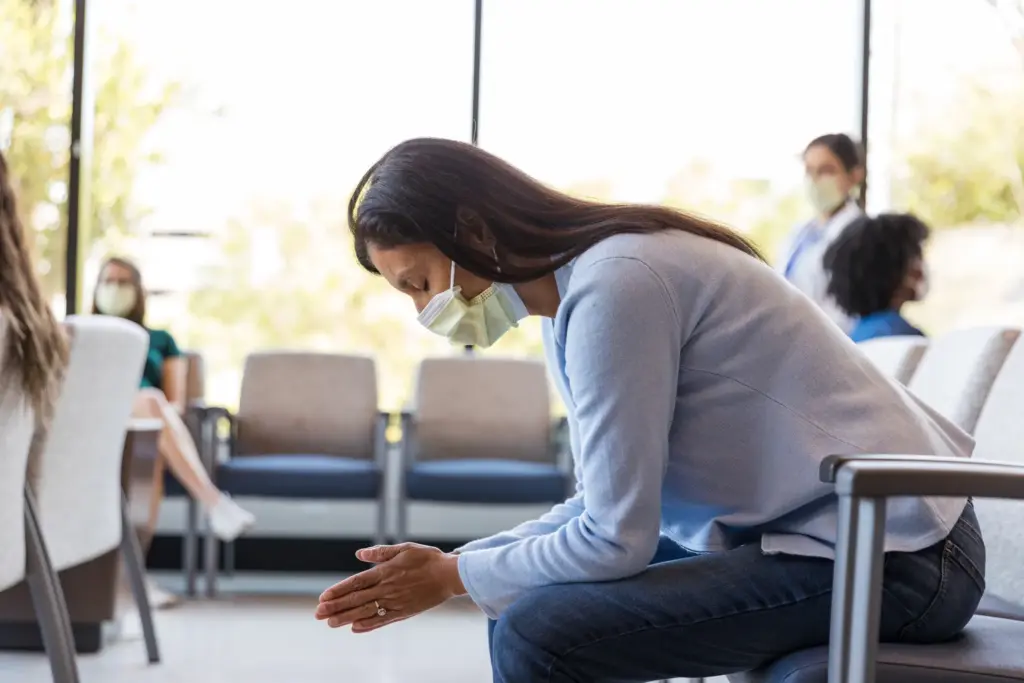 A woman with a mask waiting to see a doctor.