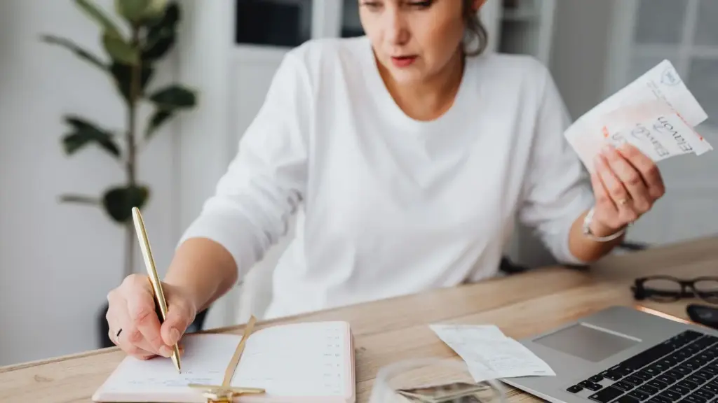 A woman recording receipts in a notebook.