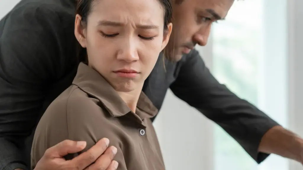 A man putting his hands around a woman's shoulder.