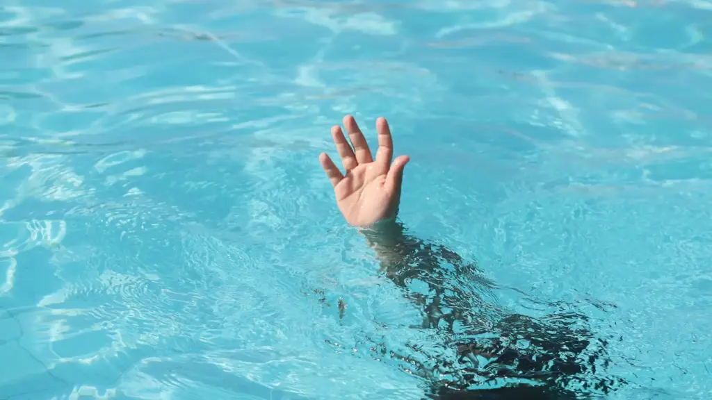 A person drowning in a pool and a person is reaching out for help.