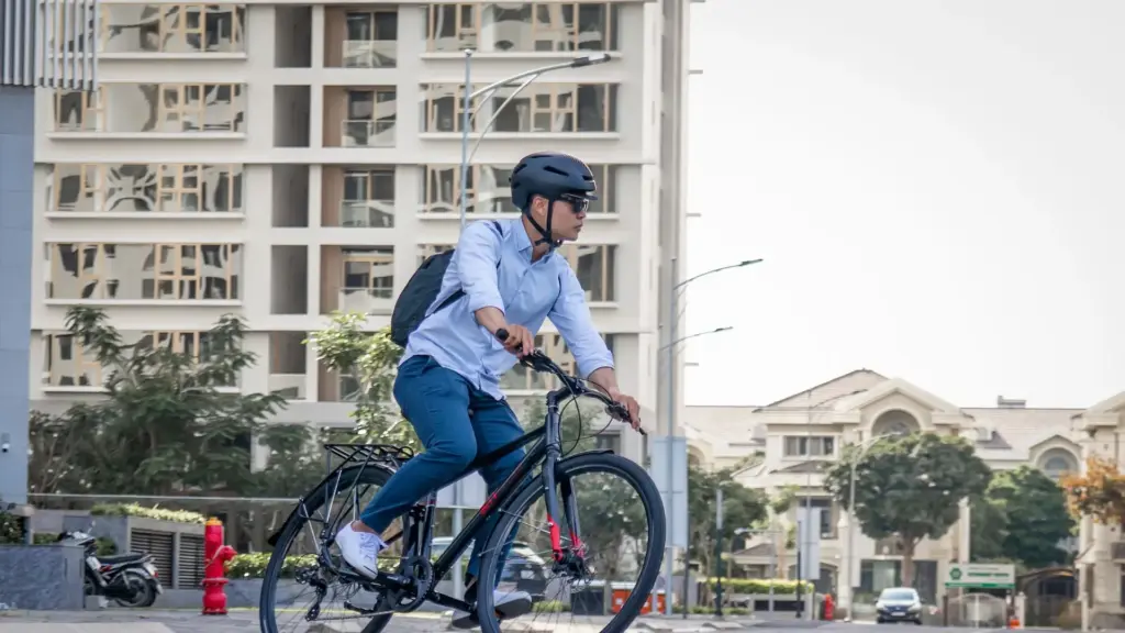 A bicyclist with a helmet riding through a street.