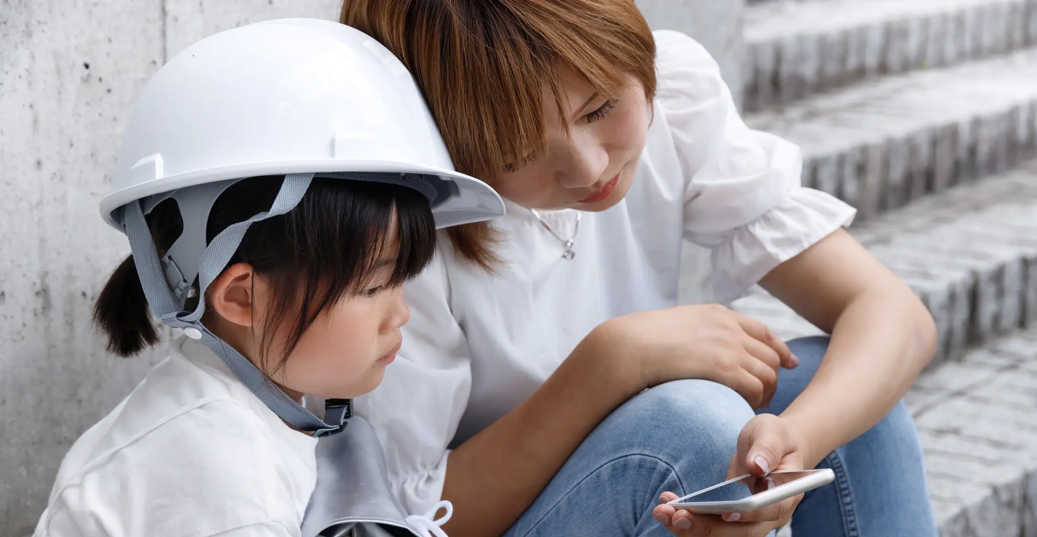 A mother and daughter looking at a smartphone.