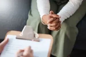 A person taking notes while a nervous woman is explaining something.