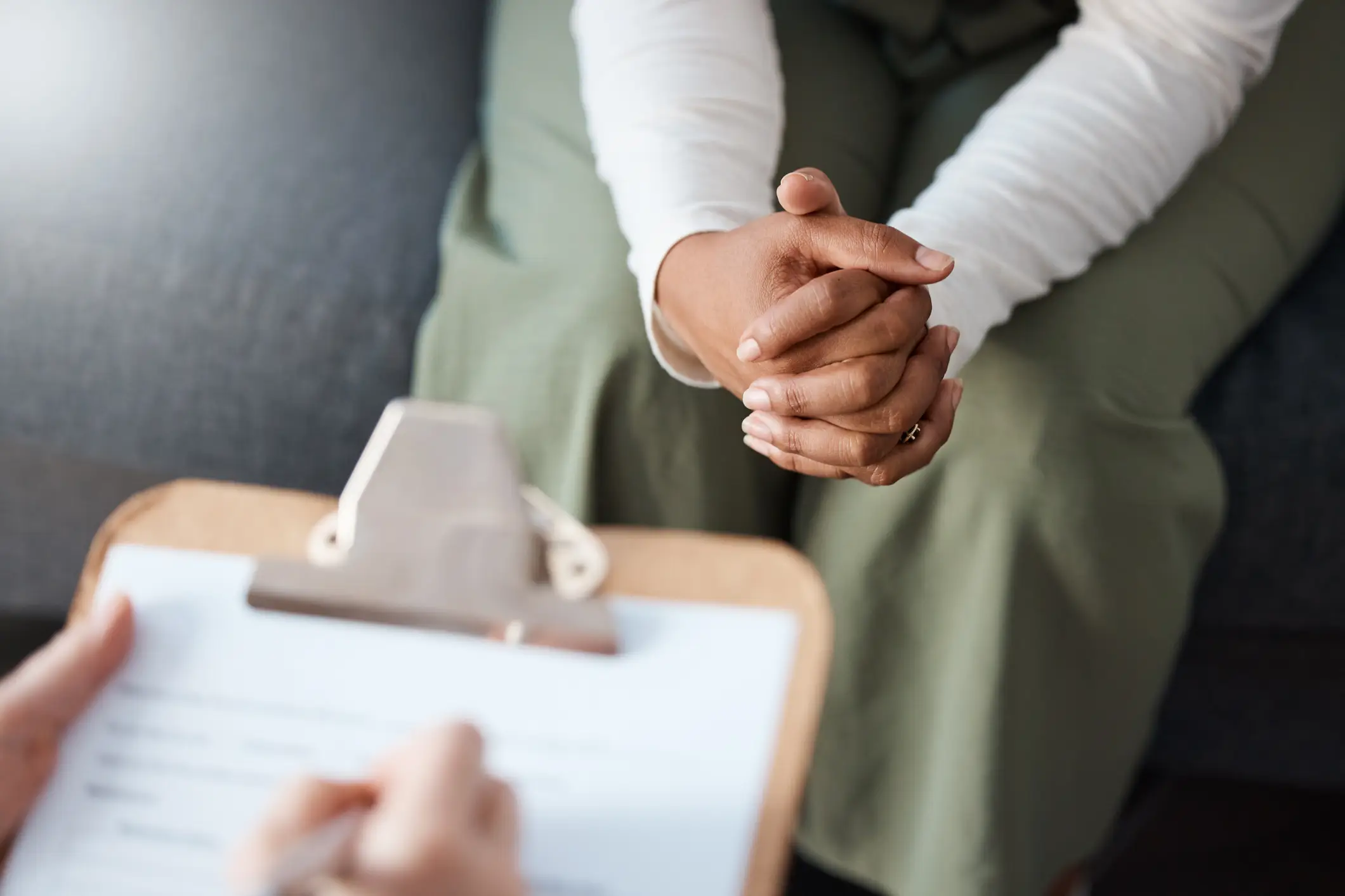 A person taking notes while a nervous woman is explaining something.
