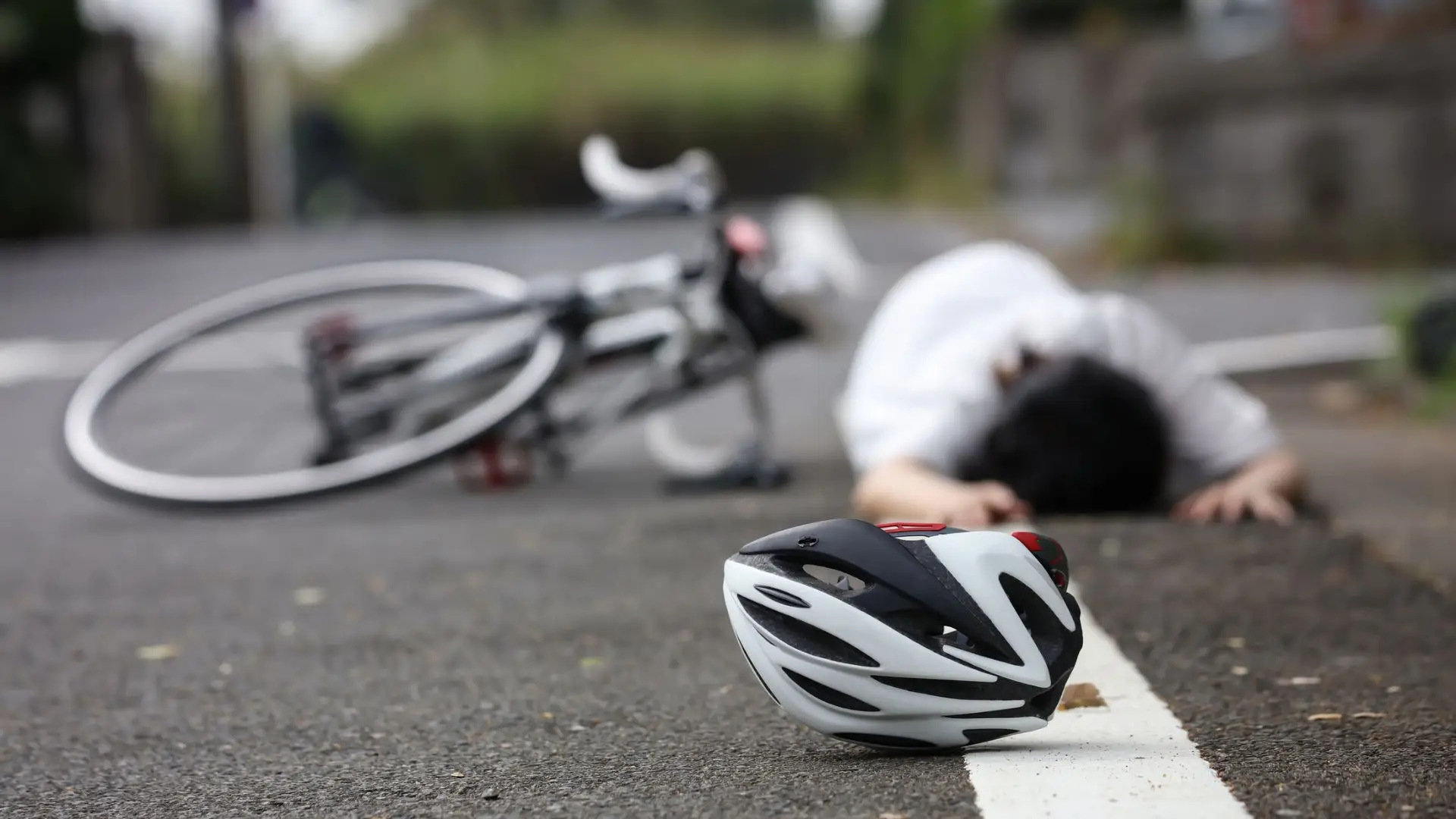 A bicyclist on the ground after getting hit by a car.