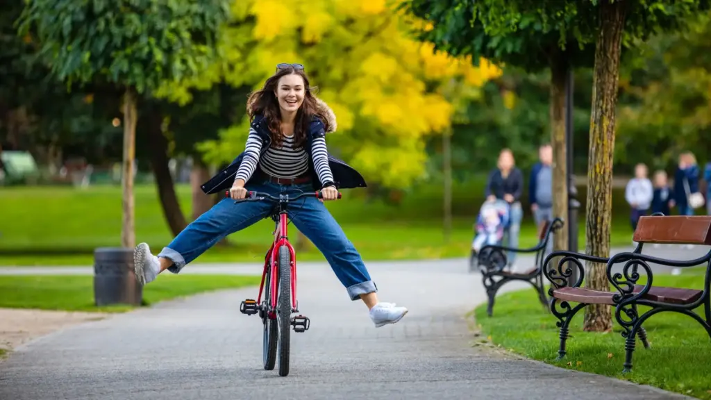 A woman having fun while riding a bike in a park.