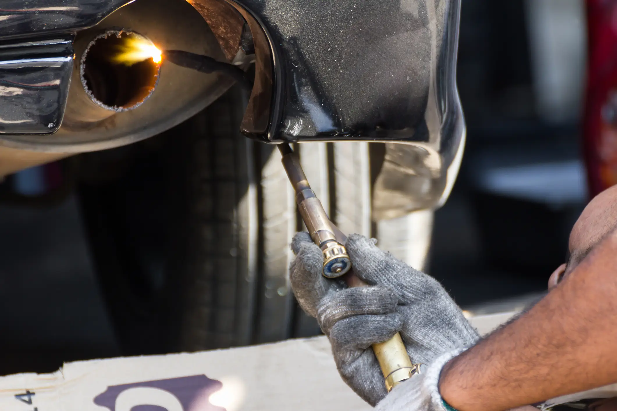 A man tampering with a car's exhaust emission.