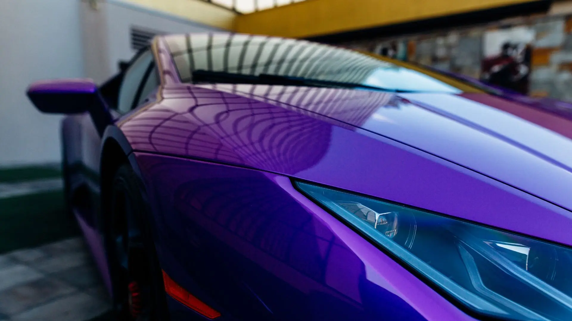 A purple sports car with a new illegal fender attached.