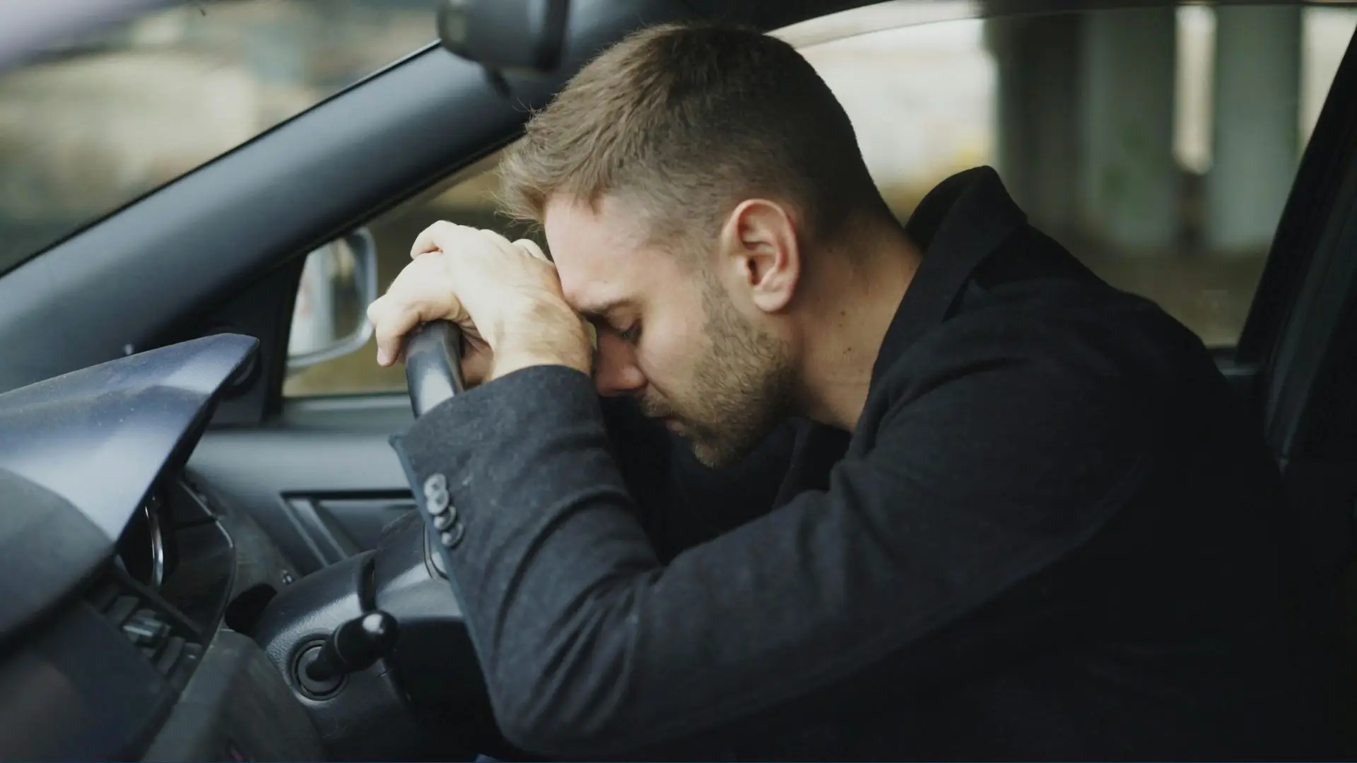 A driver resting his head on the steering wheel.
