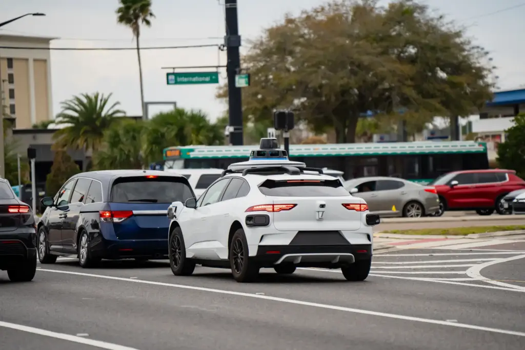 A self driving car stopped at a red light with other cars.