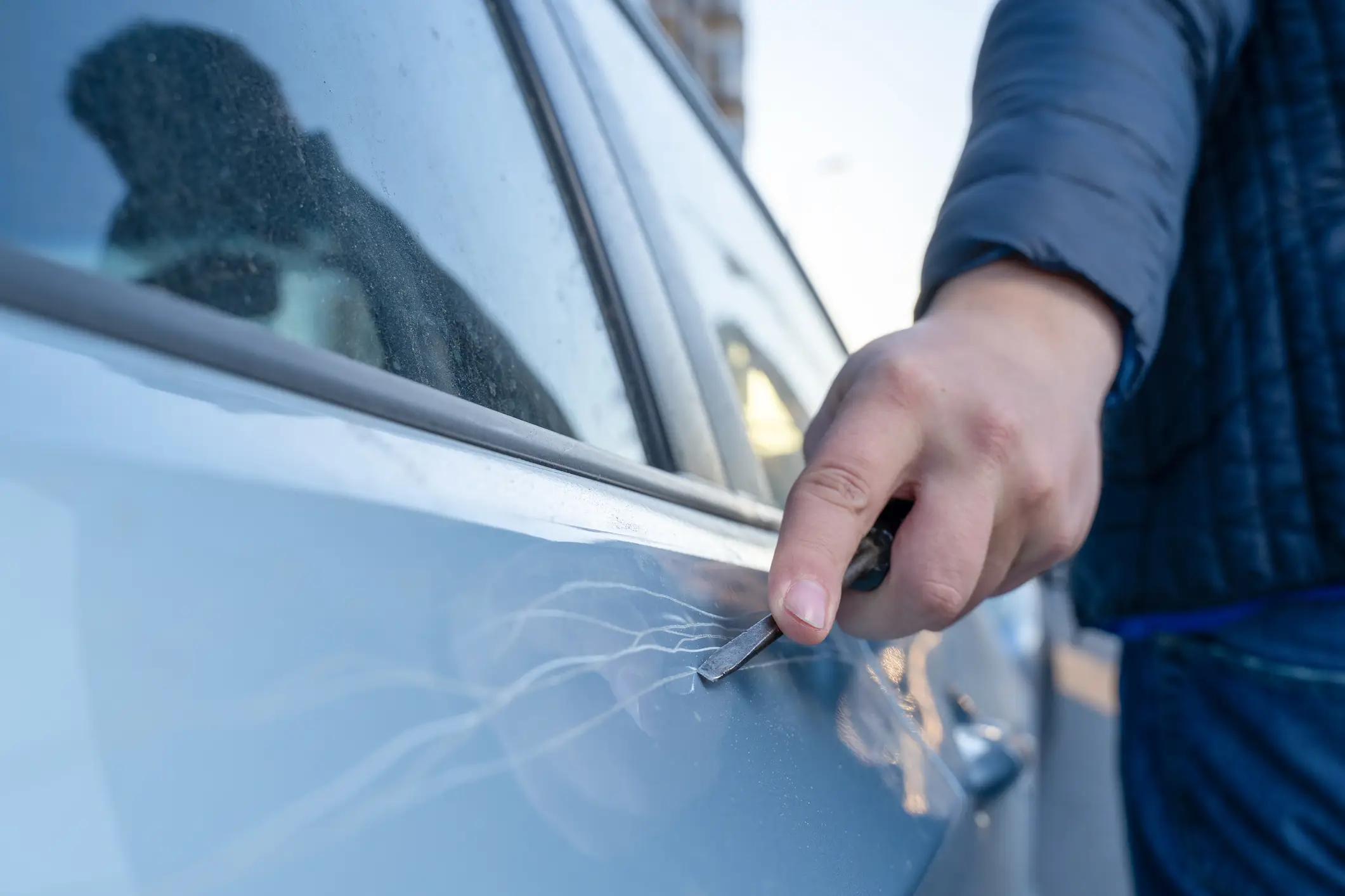 A person keying a car.