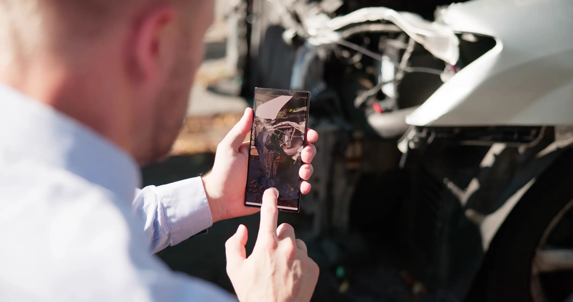 A man taking pictures of a broken car after a car accident.