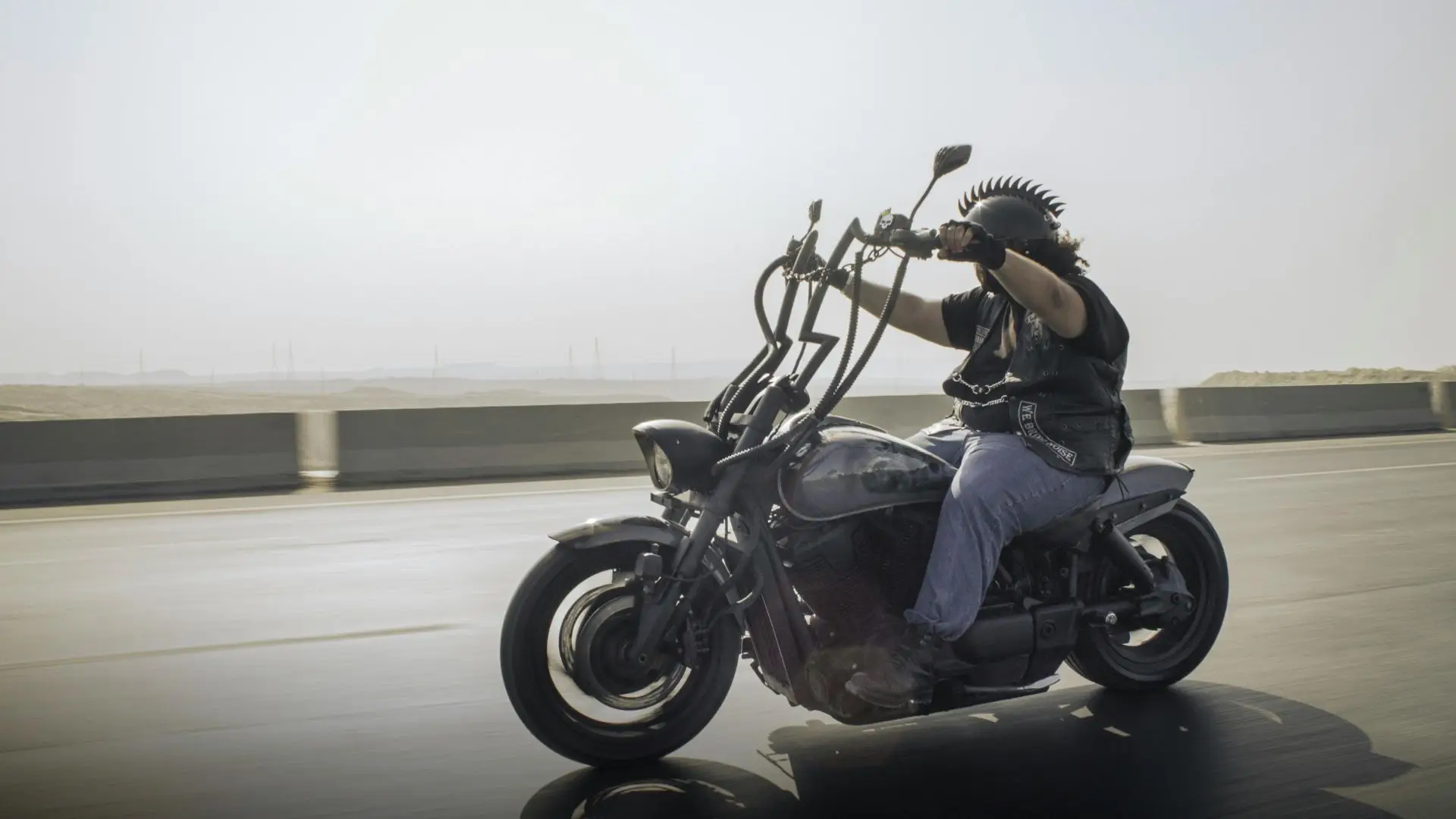A man riding a motorcycle with ape hangers.