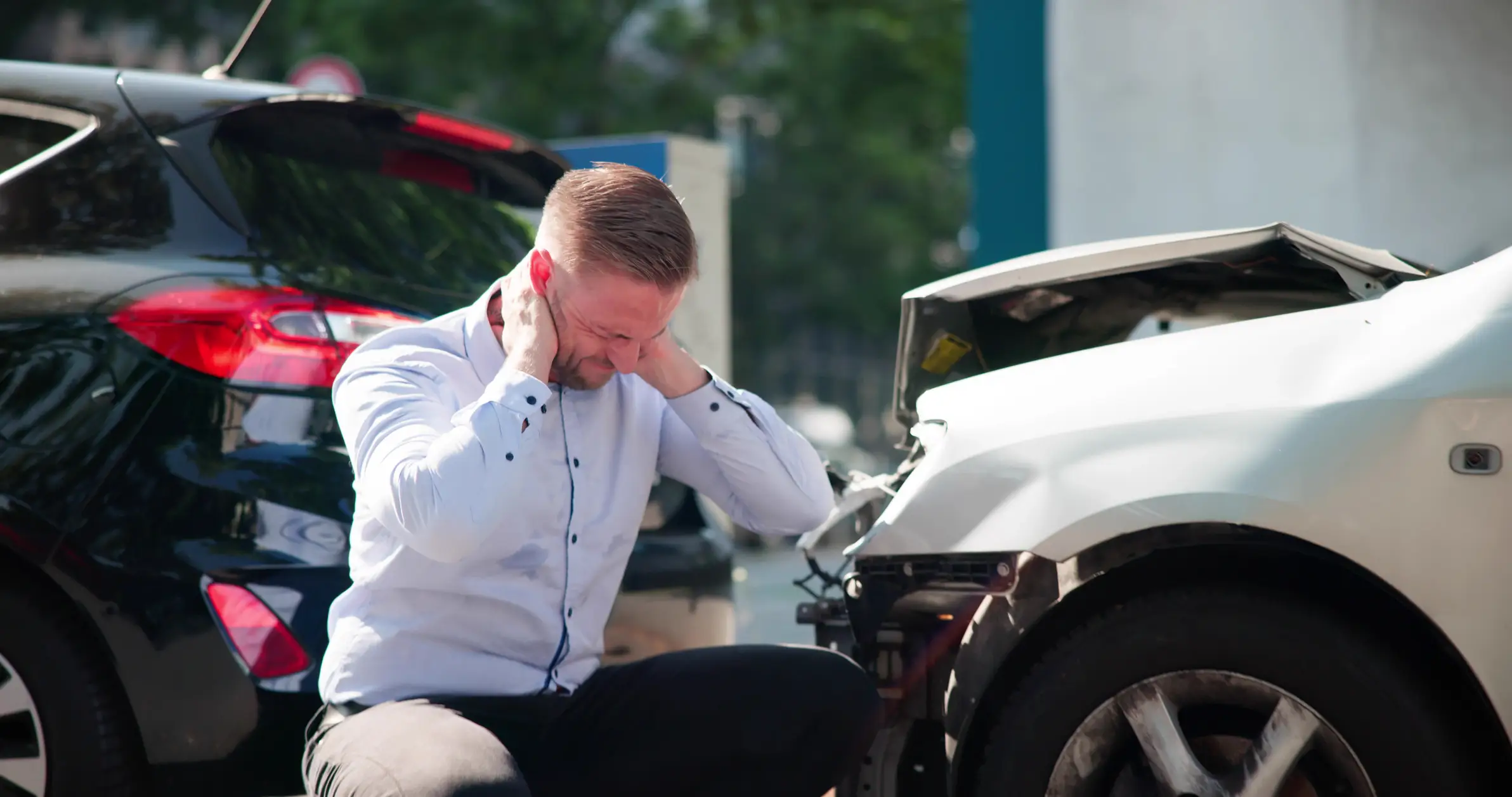 A man holding onto his neck after a rear end collision.