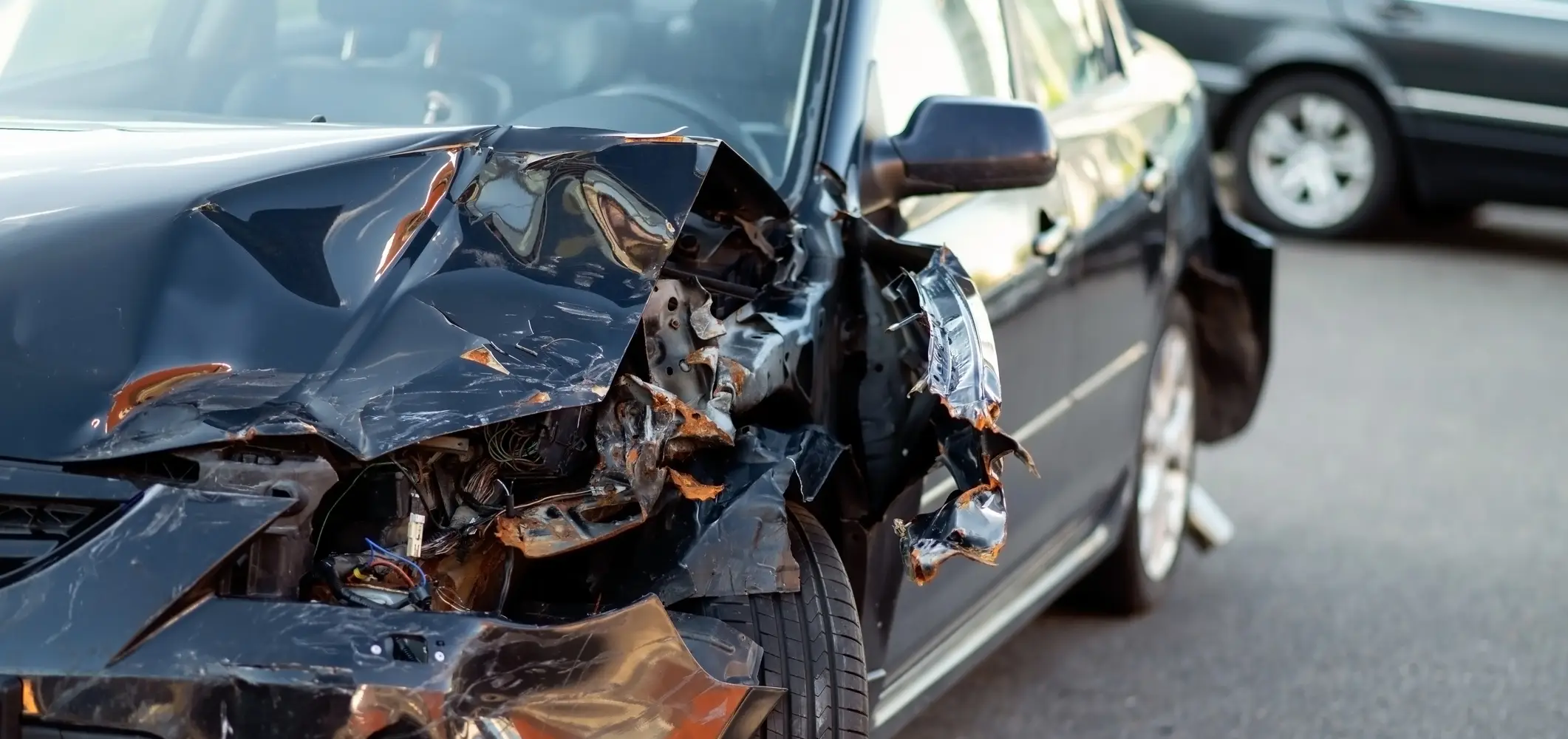 A wrecked car with a broken front bumper and light.