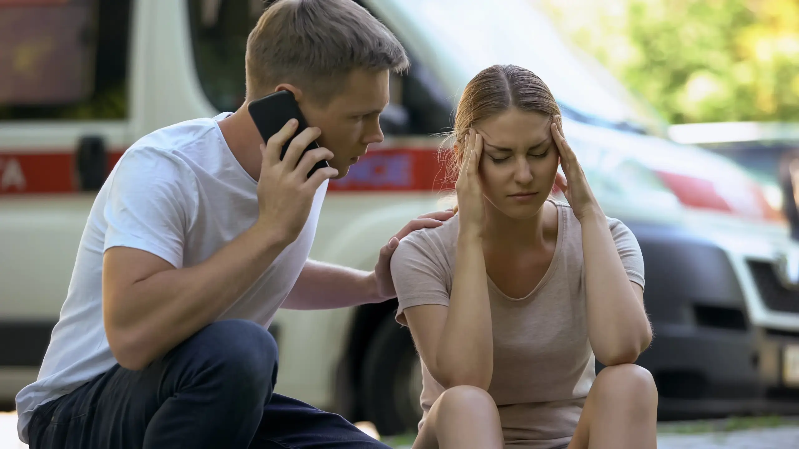 A man on the phone with 911 while with a woman experiencing headaches.