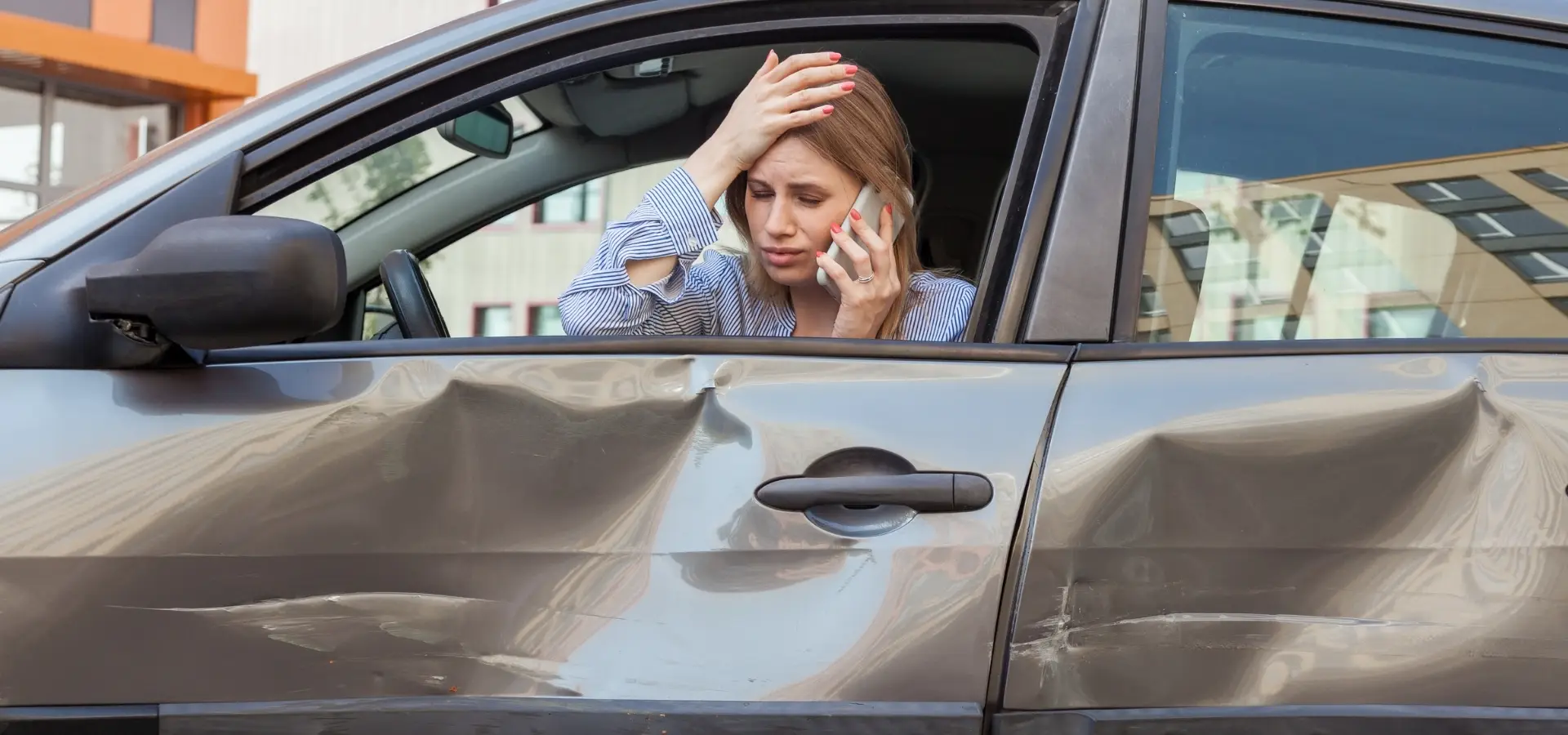 A woman on the phone after getting into a car accident.