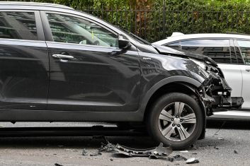 London, England - June 2022: Car with extensive damage to its front after colliding wityh a traffic light. The traffic light is wedged under the vehicle.